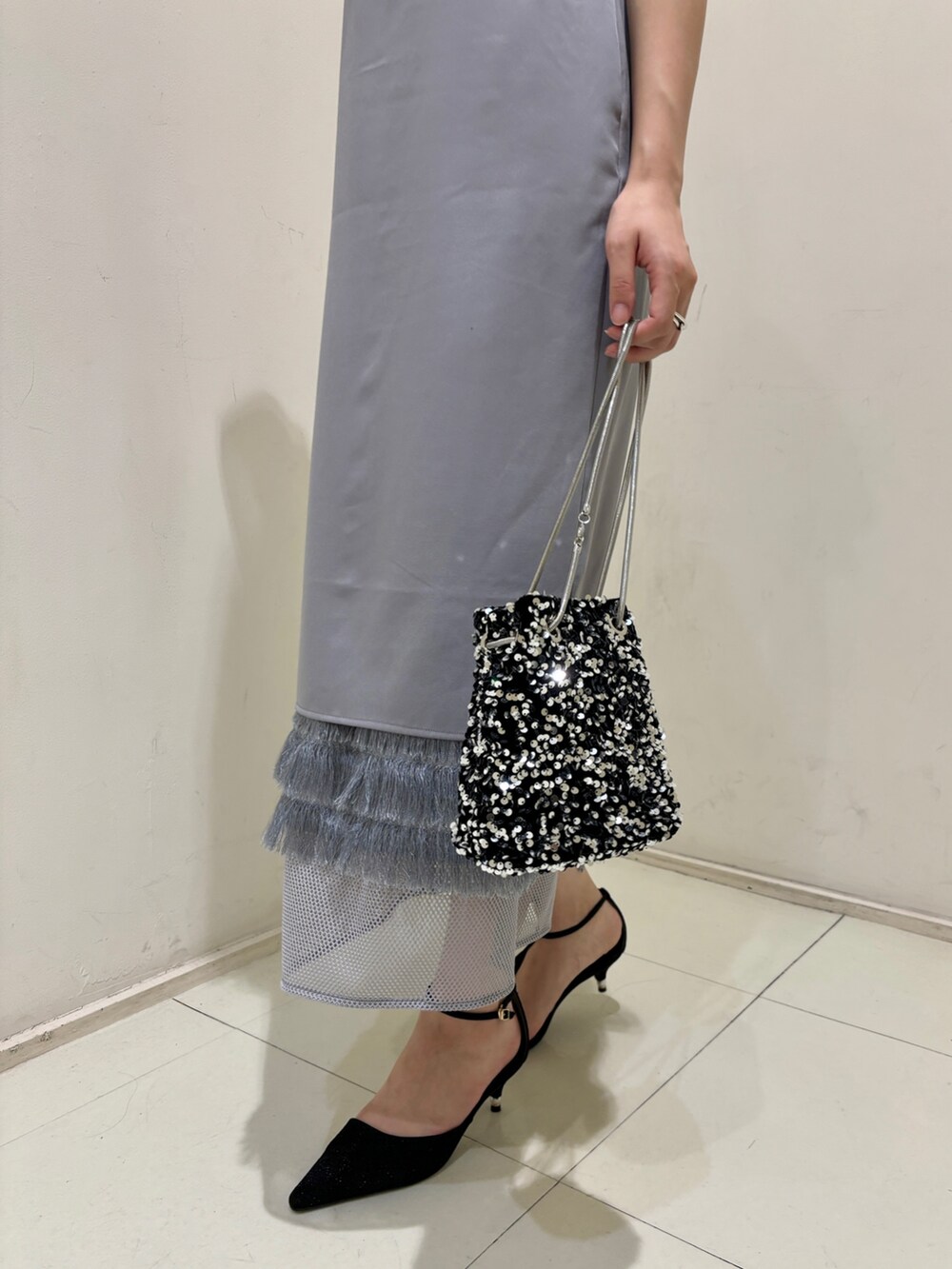 シルバー系のハンドバッグ、ブラック系のパンプス、パープル系のドレスを着用したレディースの夏コーディネートの6枚目の写真