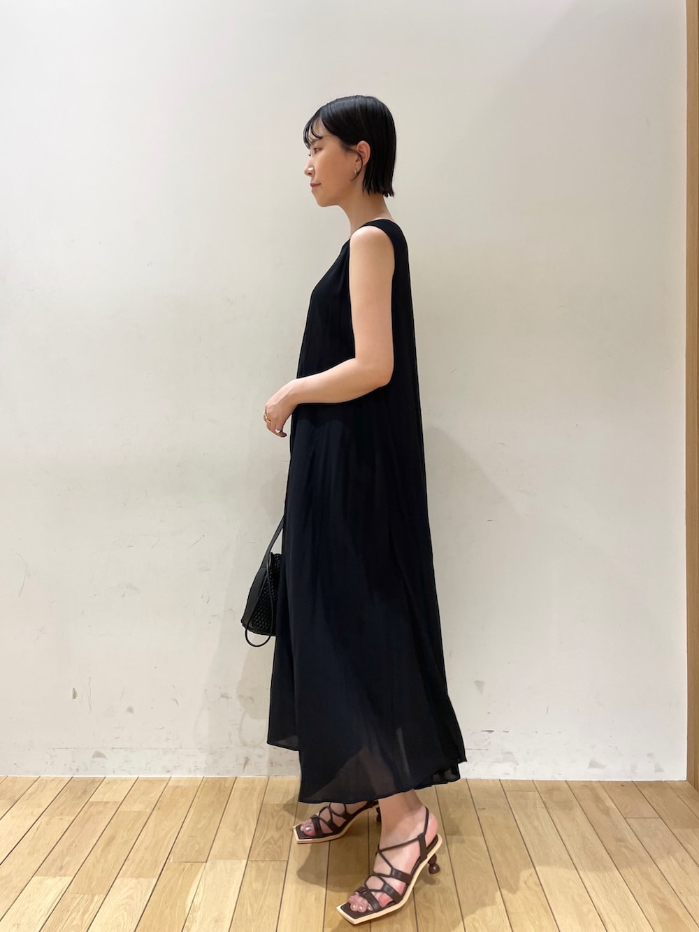 ブラック系のワンピース、ブラック系のハンドバッグ、ブラウン系のサンダルを着用したレディースの夏コーディネートの6枚目の写真