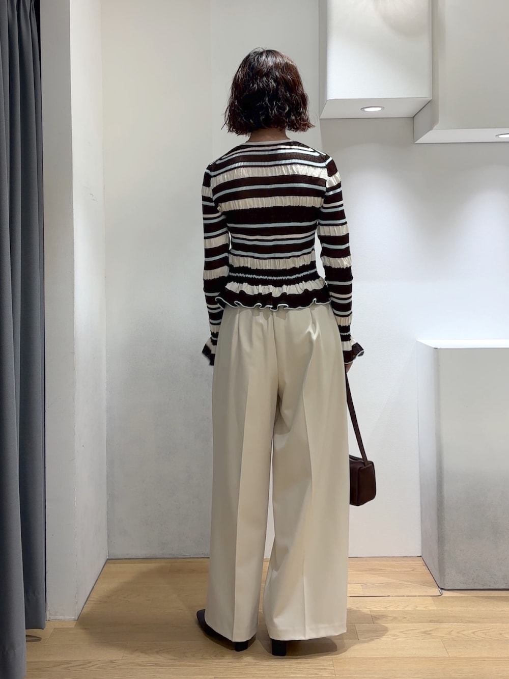 ホワイト系のその他パンツ、ブラウン系のカーディガン/ボレロ、ブラック系のブーツを着用したレディースの秋コーディネートの4枚目の写真