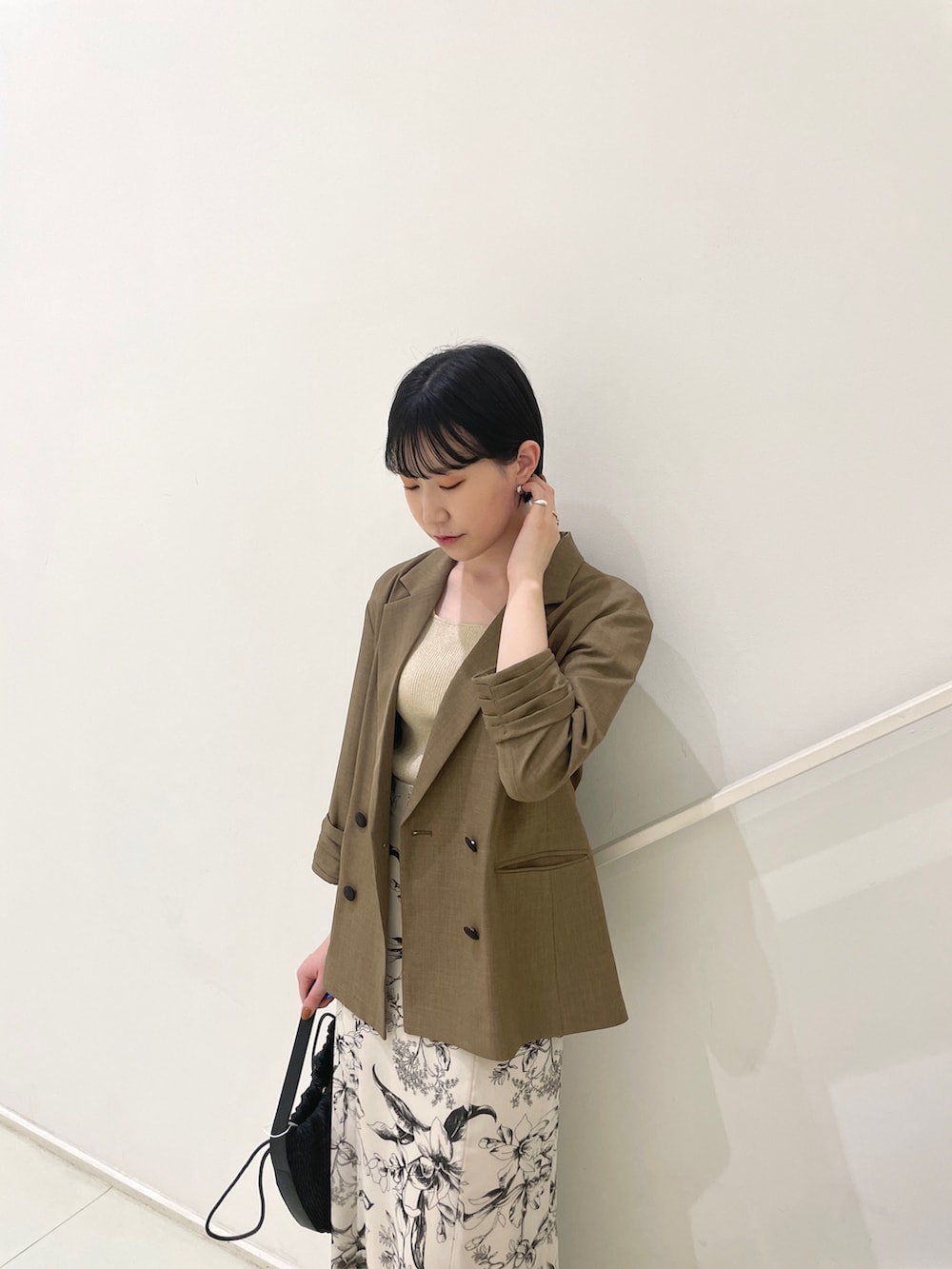 ブラウン系のテーラードジャケット、ベージュ系のニット/セーター、ホワイト系のスカートを着用したレディースの春コーディネートの5枚目の写真