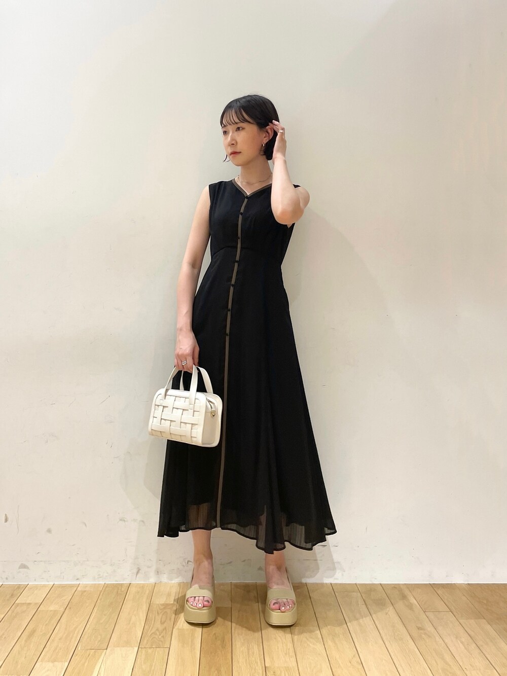ホワイト系のショルダーバッグ、ベージュ系のサンダル、ブラック系のワンピースを着用したレディースの夏コーディネートの2枚目の写真