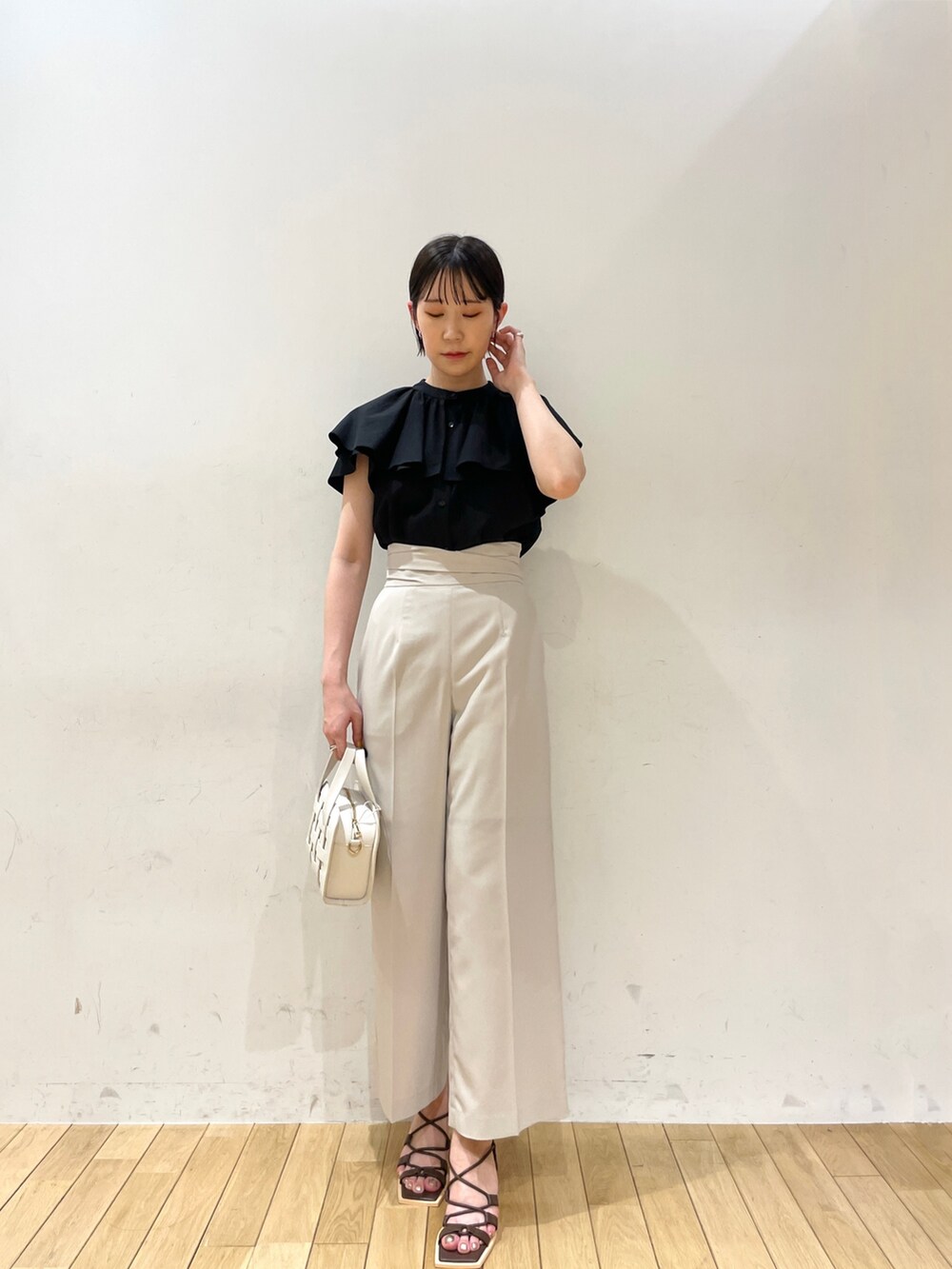ブラック系のシャツ/ブラウス、ホワイト系のスラックス、ホワイト系のショルダーバッグを着用したレディースの夏コーディネートの2枚目の写真
