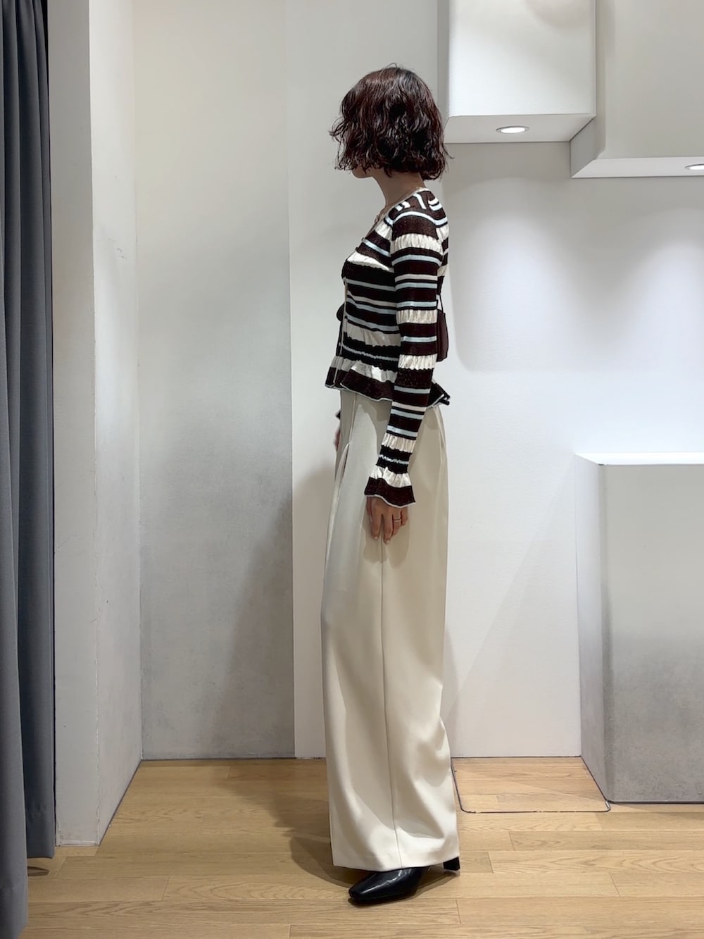 ホワイト系のその他パンツ、ブラウン系のカーディガン/ボレロ、ブラック系のブーツを着用したレディースの秋コーディネートの3枚目の写真