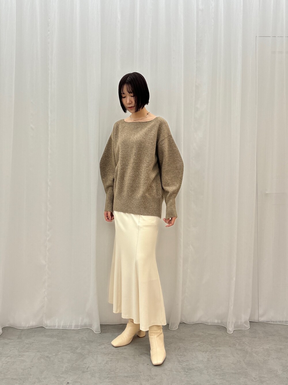 ブラウン系のニット/セーター、ホワイト系のスカートを着用したレディースの秋コーディネートの3枚目の写真