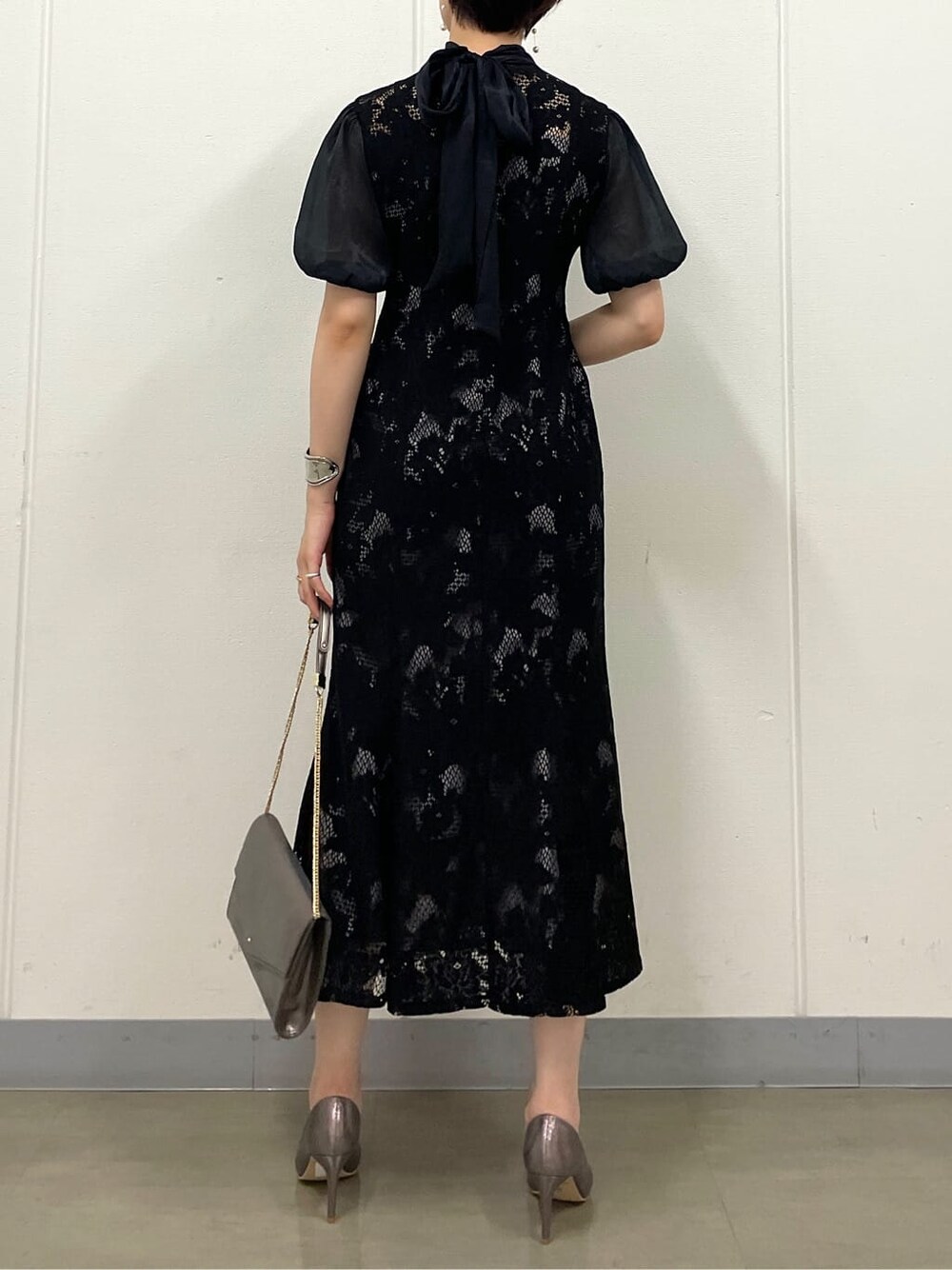 シルバー系のクラッチバッグ、シルバー系のパンプス、ブラック系のドレスを着用したレディースの夏コーディネートの6枚目の写真