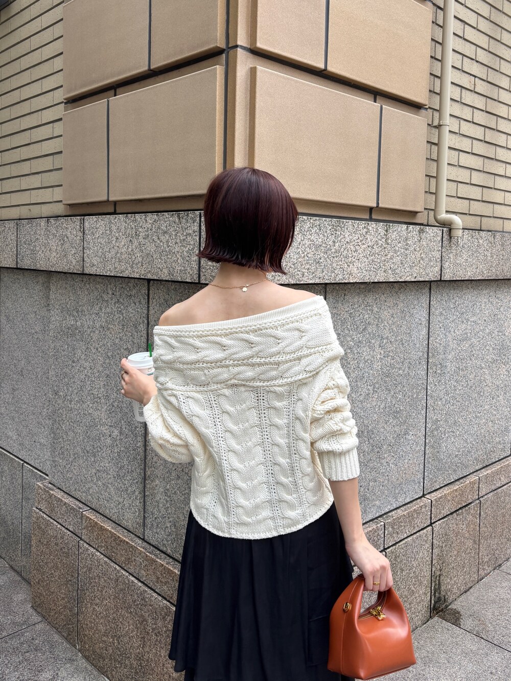 ホワイト系のニット/セーター、ブラック系のスカート、ブラウン系のハンドバッグを着用したレディースの秋コーディネートの6枚目の写真