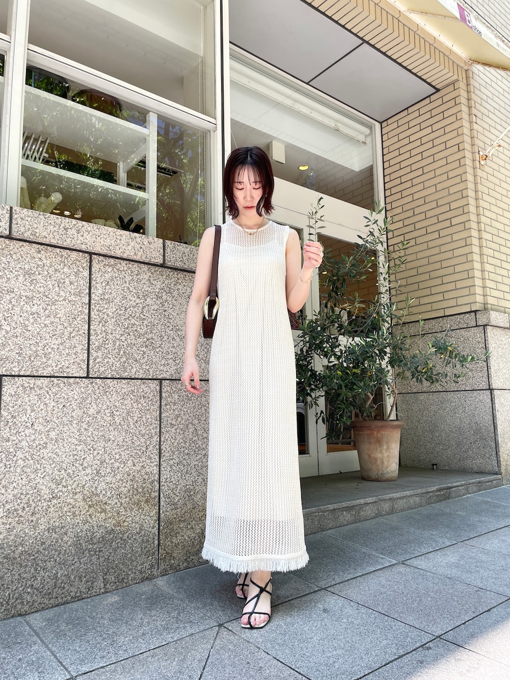 ブラック系のサンダル、ホワイト系のワンピース、ブラウン系のショルダーバッグを着用したレディースの夏コーディネートの2枚目の写真