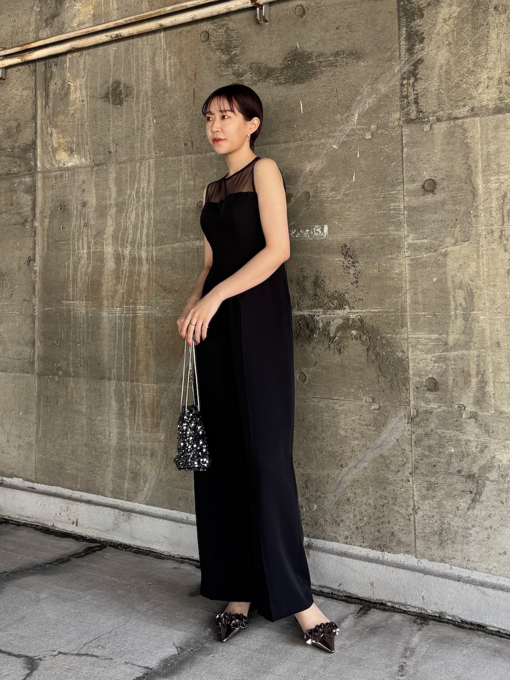 ブラック系のパンツドレス、シルバー系のショルダーバッグ、その他のパンプスを着用したレディースの春コーディネートの4枚目の写真