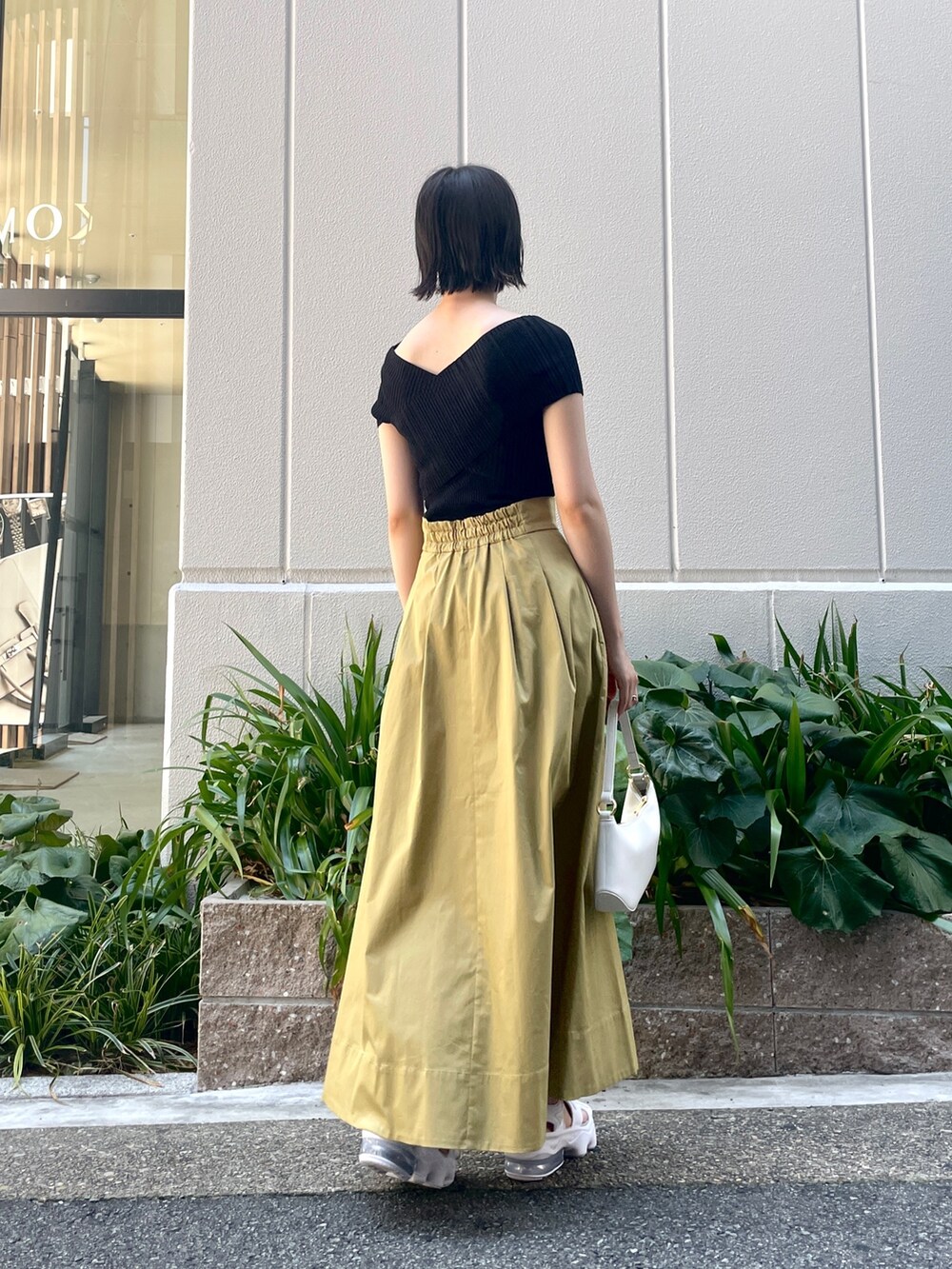 ブラック系のニット/セーター、イエロー系のスカート、ホワイト系のハンドバッグを着用したレディースの夏コーディネートの2枚目の写真