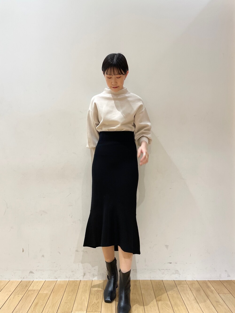 ブラック系のスカート、ホワイト系のニット/セーター、ブラック系のブーツを着用したレディースの冬コーディネートの3枚目の写真