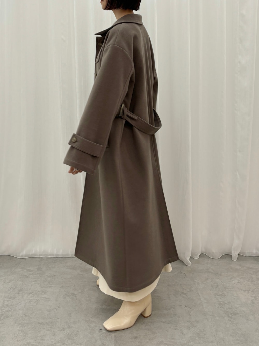 ホワイト系のスカート、ブラウン系のニット/セーター、ブラウン系のステンカラーコートを着用したレディースの秋コーディネートの4枚目の写真