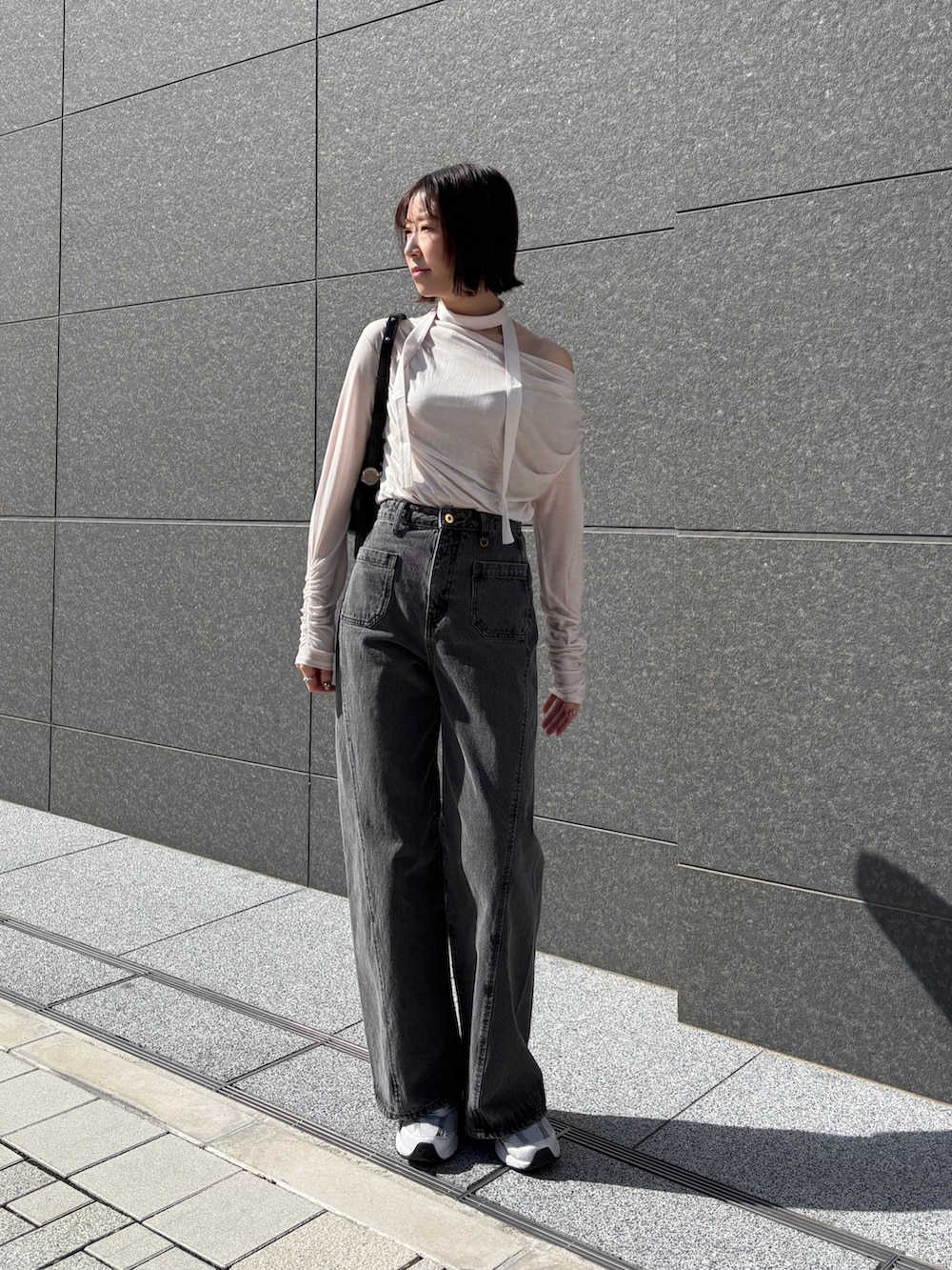 ブラック系のデニムパンツ、ホワイト系のTシャツ/カットソー、ブラック系のハンドバッグを着用したレディースの春コーディネートの2枚目の写真