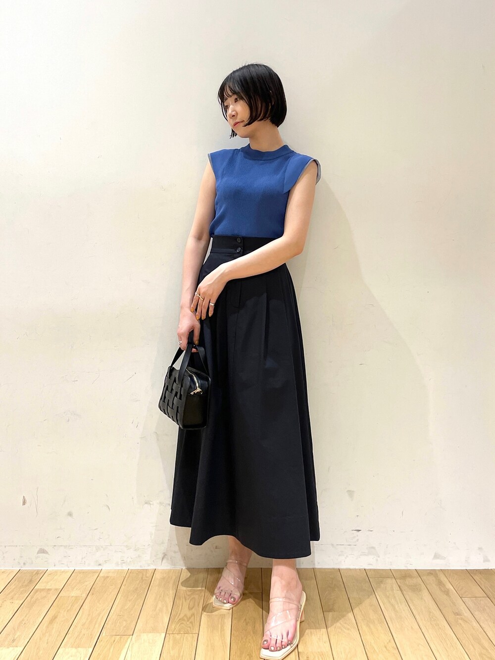 ブルー系のスカート、ブルー系のニット/セーター、ブラック系のショルダーバッグを着用したレディースの夏コーディネートの2枚目の写真