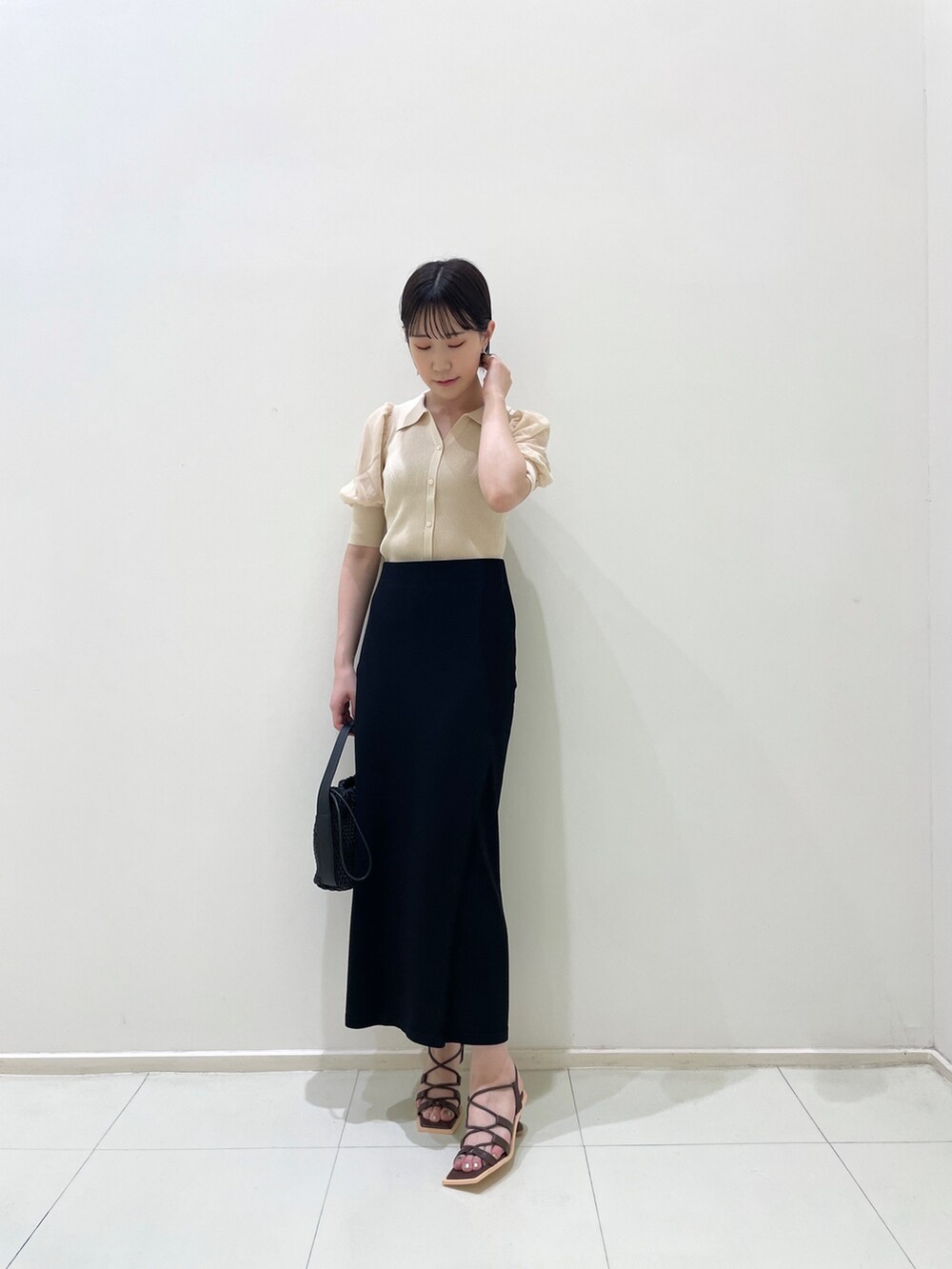 ブラック系のスカート、ホワイト系のニット/セーター、ブラック系のハンドバッグを着用したレディースの夏コーディネートの5枚目の写真