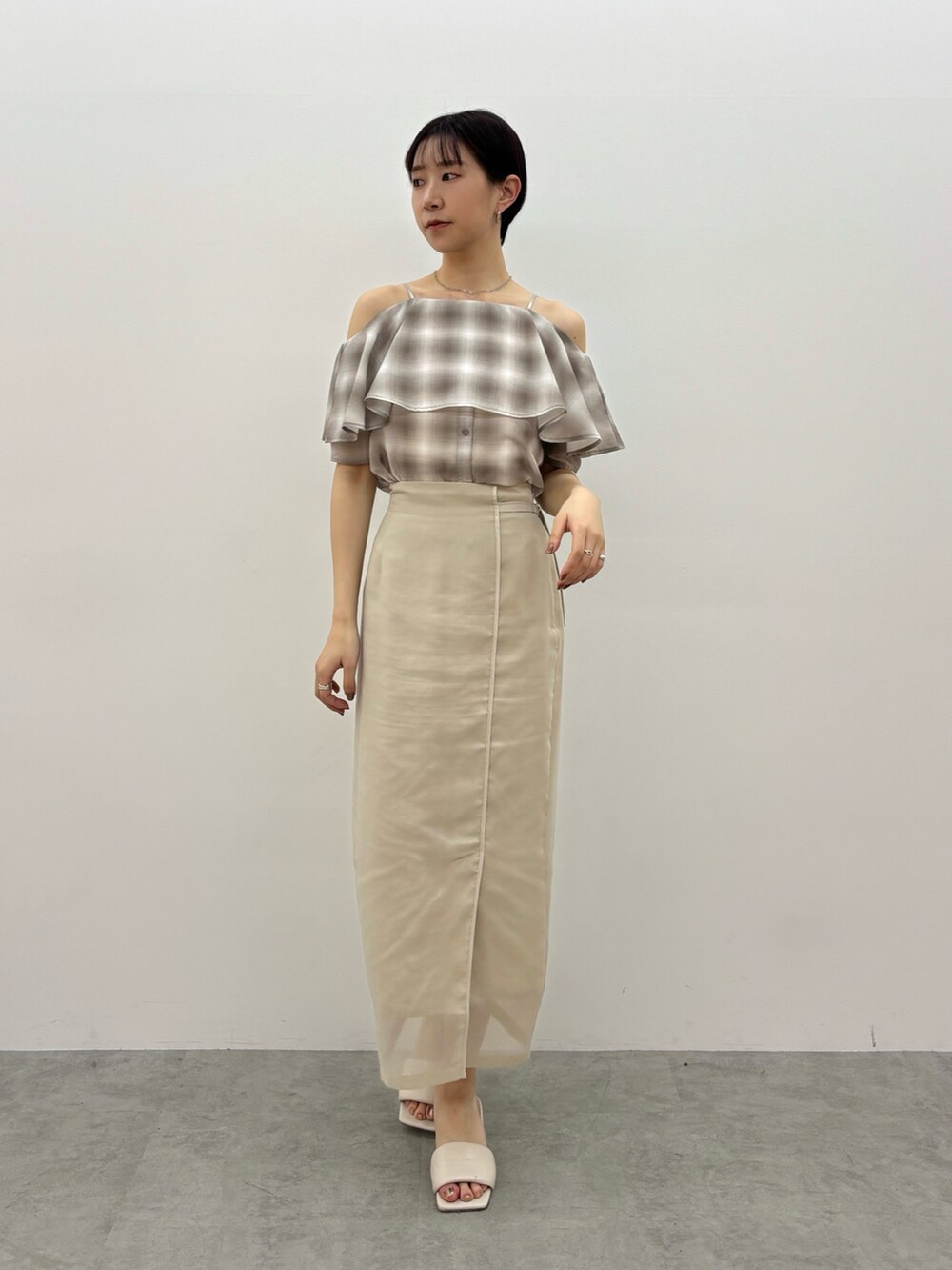 ベージュ系のシャツ/ブラウス、ホワイト系のスカート、ホワイト系のサンダルを着用したレディースの春コーディネートの2枚目の写真