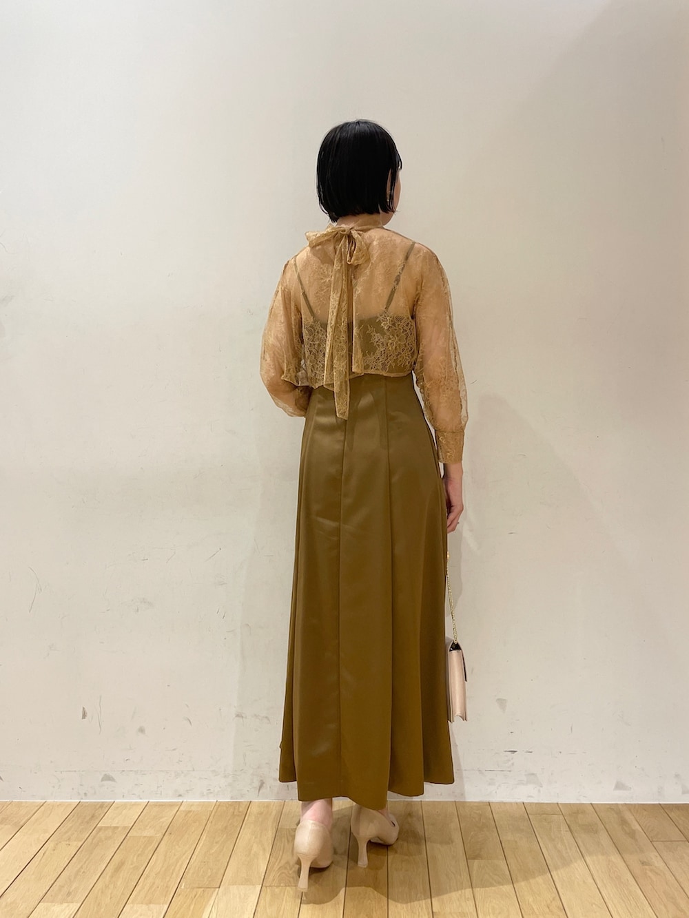 ブラウン系のドレス、ベージュ系のクラッチバッグ、ベージュ系のパンプスを着用したレディースの夏コーディネートの4枚目の写真