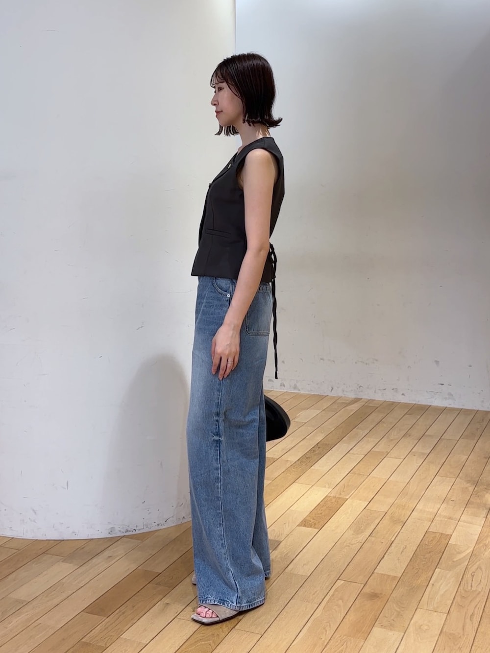 グレー系のワンピース、ブルー系のデニムパンツ、ブラック系のハンドバッグを着用したレディースの夏コーディネートの3枚目の写真