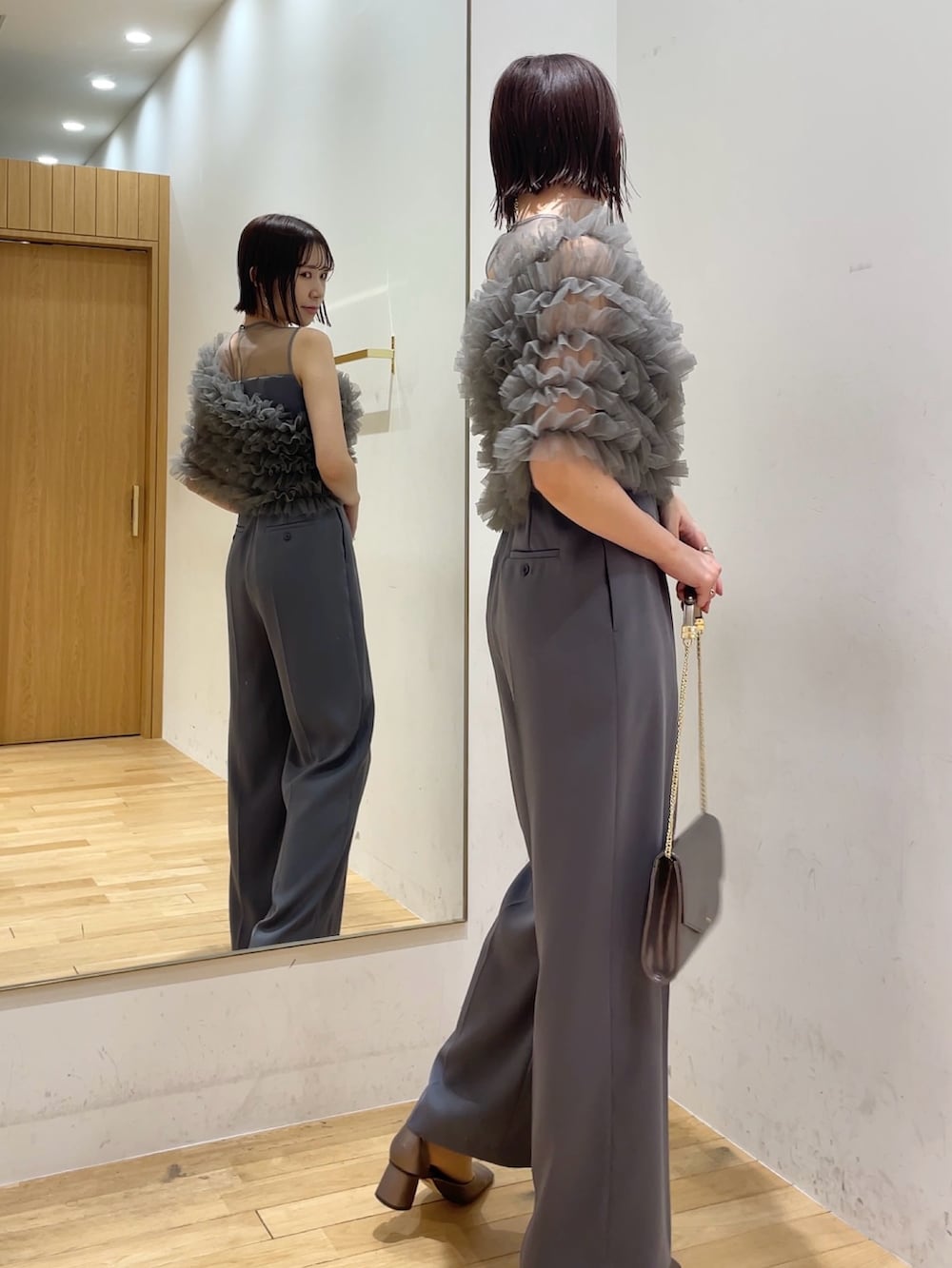 シルバー系のハンドバッグ、その他のパンプス、グレー系のパンツドレスを着用したレディースの冬コーディネートの2枚目の写真