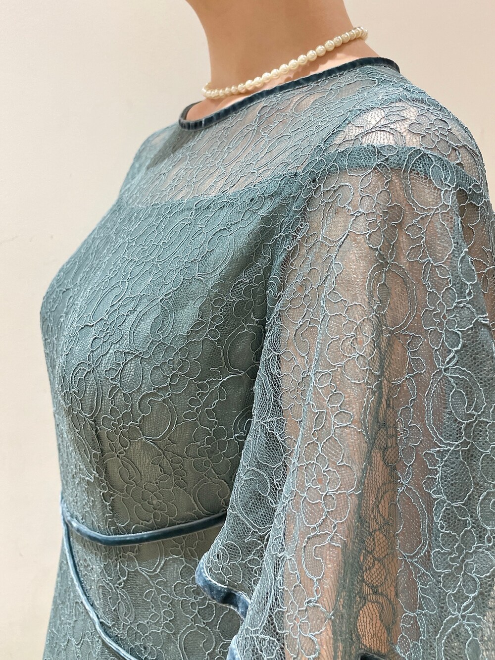 グリーン系のドレス、ベージュ系のクラッチバッグ、ゴールド系のパンプスを着用したレディースの冬コーディネートの8枚目の写真