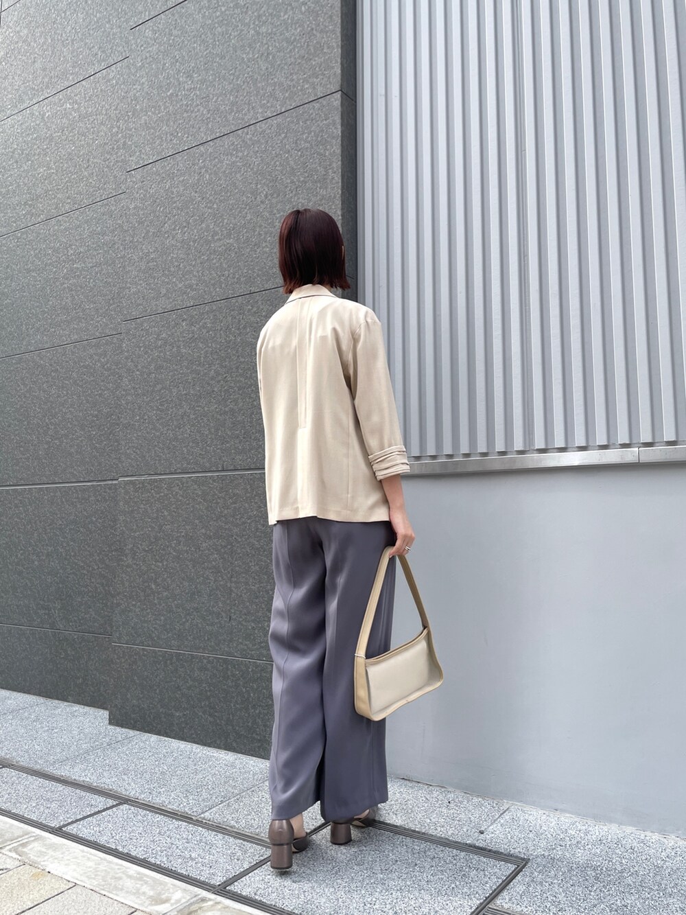 グレー系のパンツドレス、その他のパンプス、ベージュ系のテーラードジャケットを着用したレディースの春コーディネートの5枚目の写真