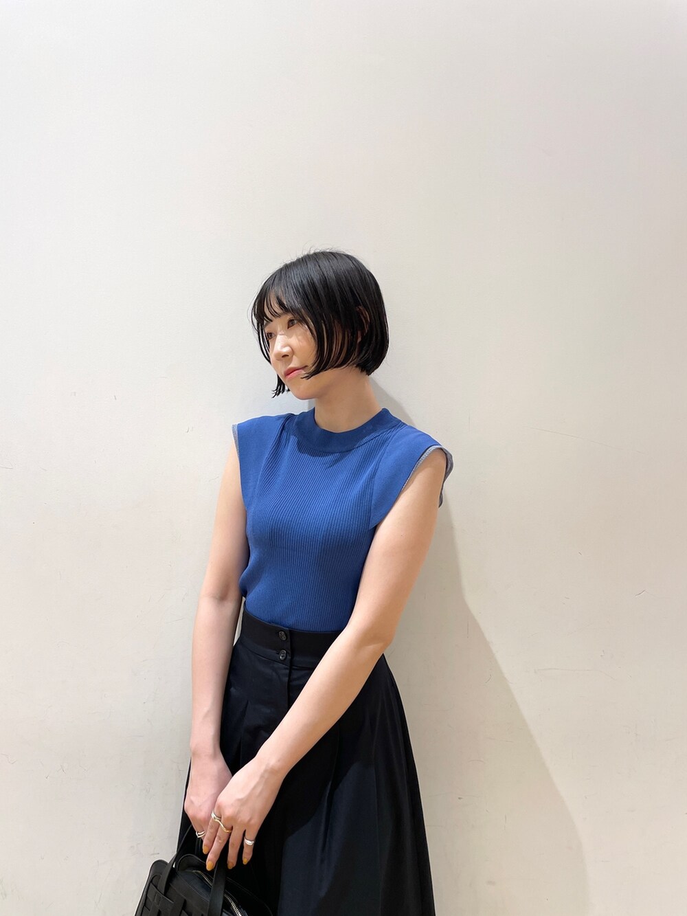 ブルー系のスカート、ブルー系のニット/セーター、ブラック系のショルダーバッグを着用したレディースの夏コーディネートの6枚目の写真