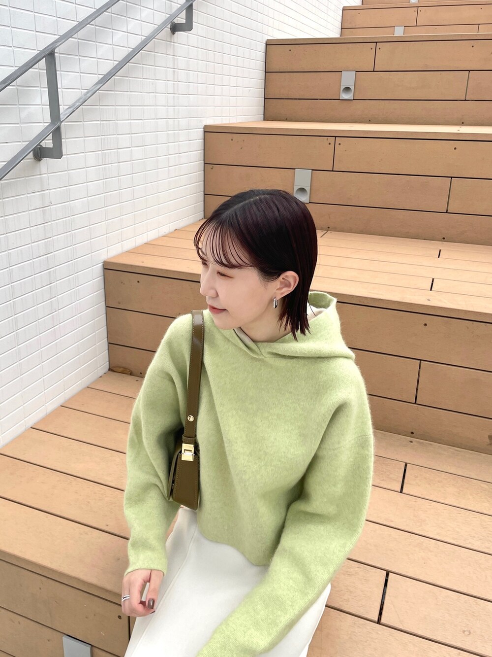 ホワイト系のスカート、グリーン系のパーカー、ホワイト系のブーツを着用したレディースの秋コーディネートの5枚目の写真