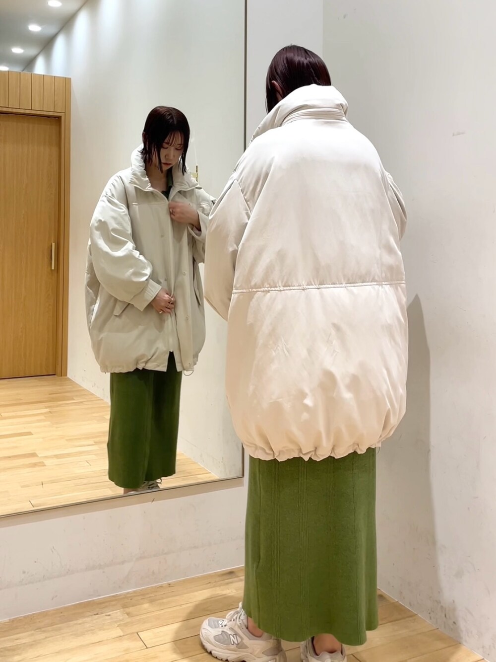 グリーン系のワンピース、ホワイト系のダウンジャケット/コート、ブラック系のチェスターコートを着用したレディースの冬コーディネートの2枚目の写真