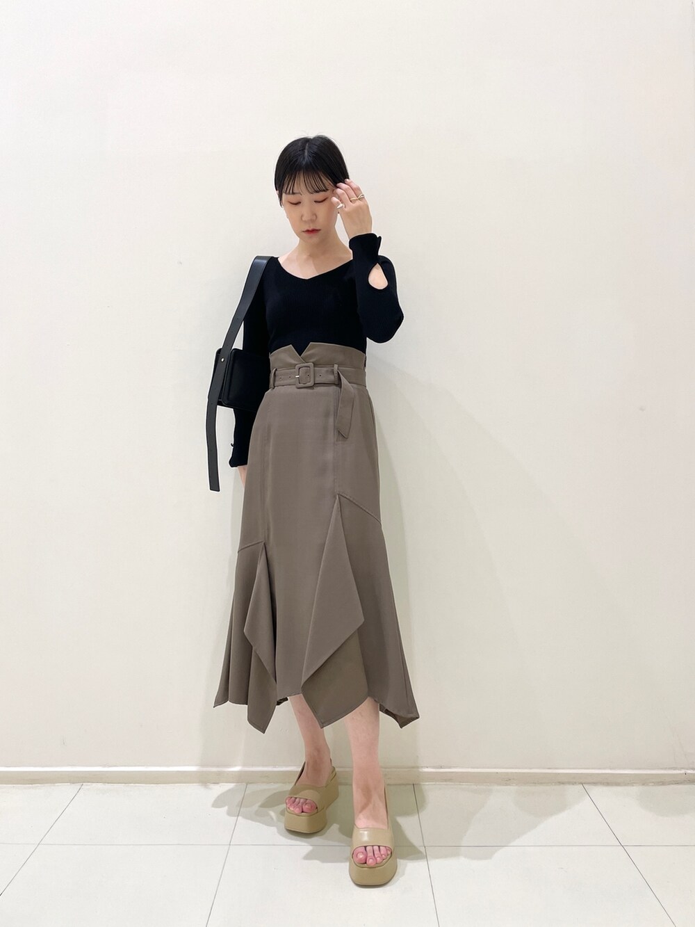 ブラウン系のスカート、ブラック系のニット/セーター、ベージュ系のサンダルを着用したレディースの春コーディネートの2枚目の写真