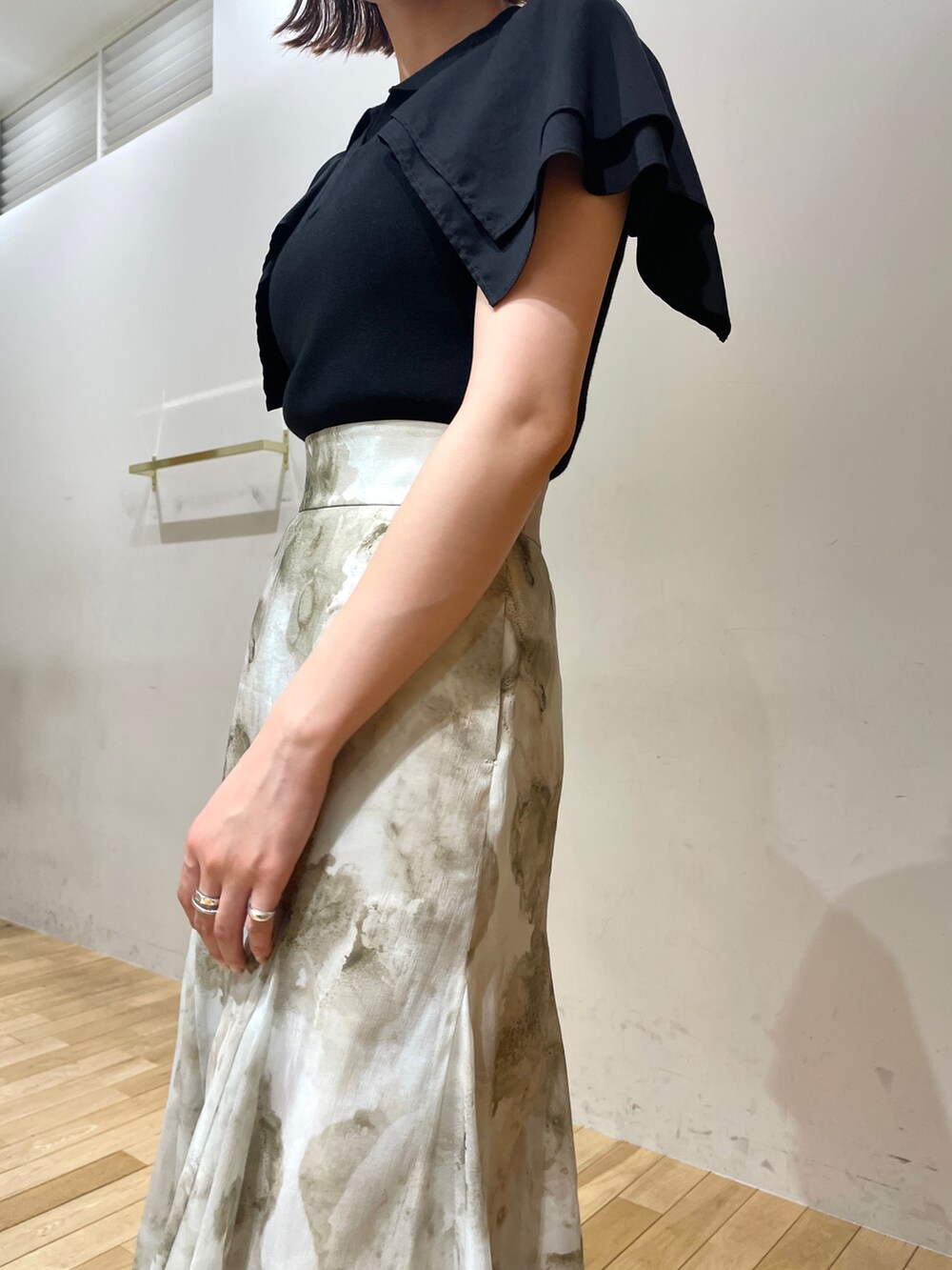 ブラック系のサンダル、グレー系のスカート、ブラック系のニット/セーターを着用したレディースの夏コーディネートの7枚目の写真