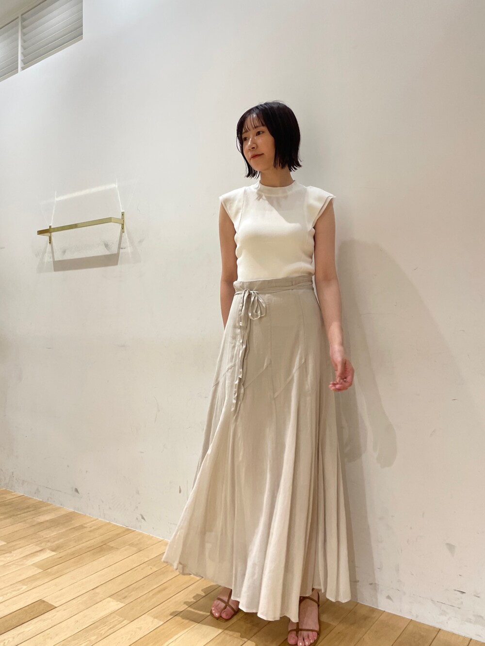 イエロー系のサンダル、グレー系のスカート、ホワイト系のニット/セーターを着用したレディースの夏コーディネートの3枚目の写真