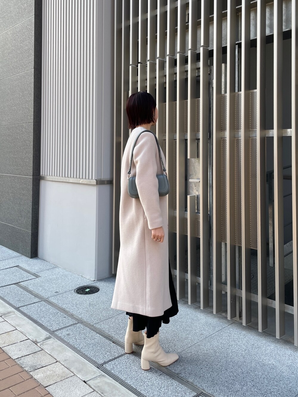 ブラック系のワンピース、ブルー系のショルダーバッグ、ホワイト系のブーツを着用したレディースの冬コーディネートの9枚目の写真