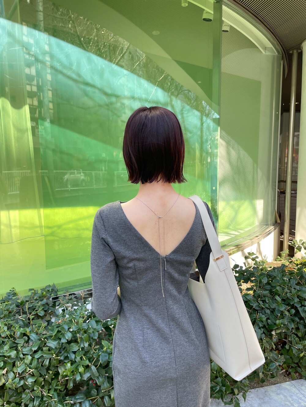 グレー系のワンピース、ホワイト系のショルダーバッグ、ホワイト系のパンプスを着用したレディースの冬コーディネートの6枚目の写真