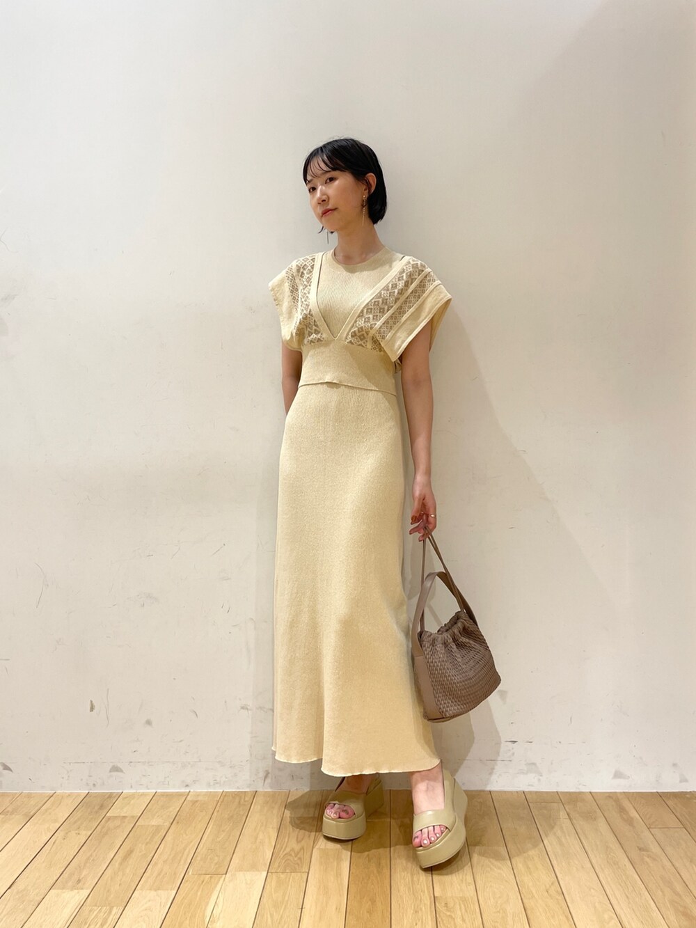 ベージュ系のワンピース、ブラウン系のハンドバッグ、ベージュ系のサンダルを着用したレディースの夏コーディネートの3枚目の写真