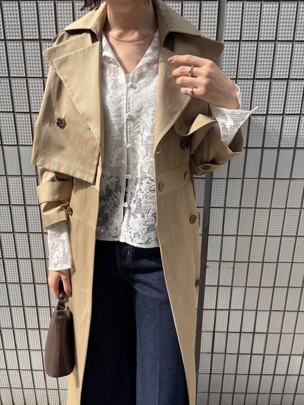 ブルー系のデニムパンツ、ベージュ系のトレンチコート、ホワイト系のシャツ/ブラウスを着用したレディースの冬コーディネートの2枚目の写真