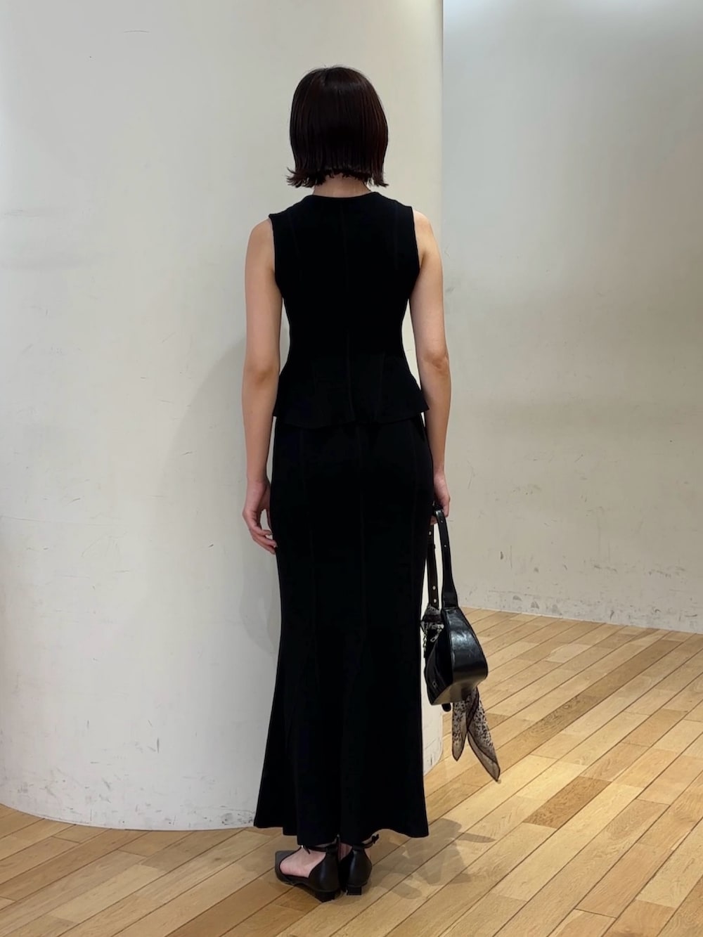 ブラック系のスカート、ブラック系のハンドバッグ、ブラック系のパンプスを着用したレディースの夏コーディネートの4枚目の写真