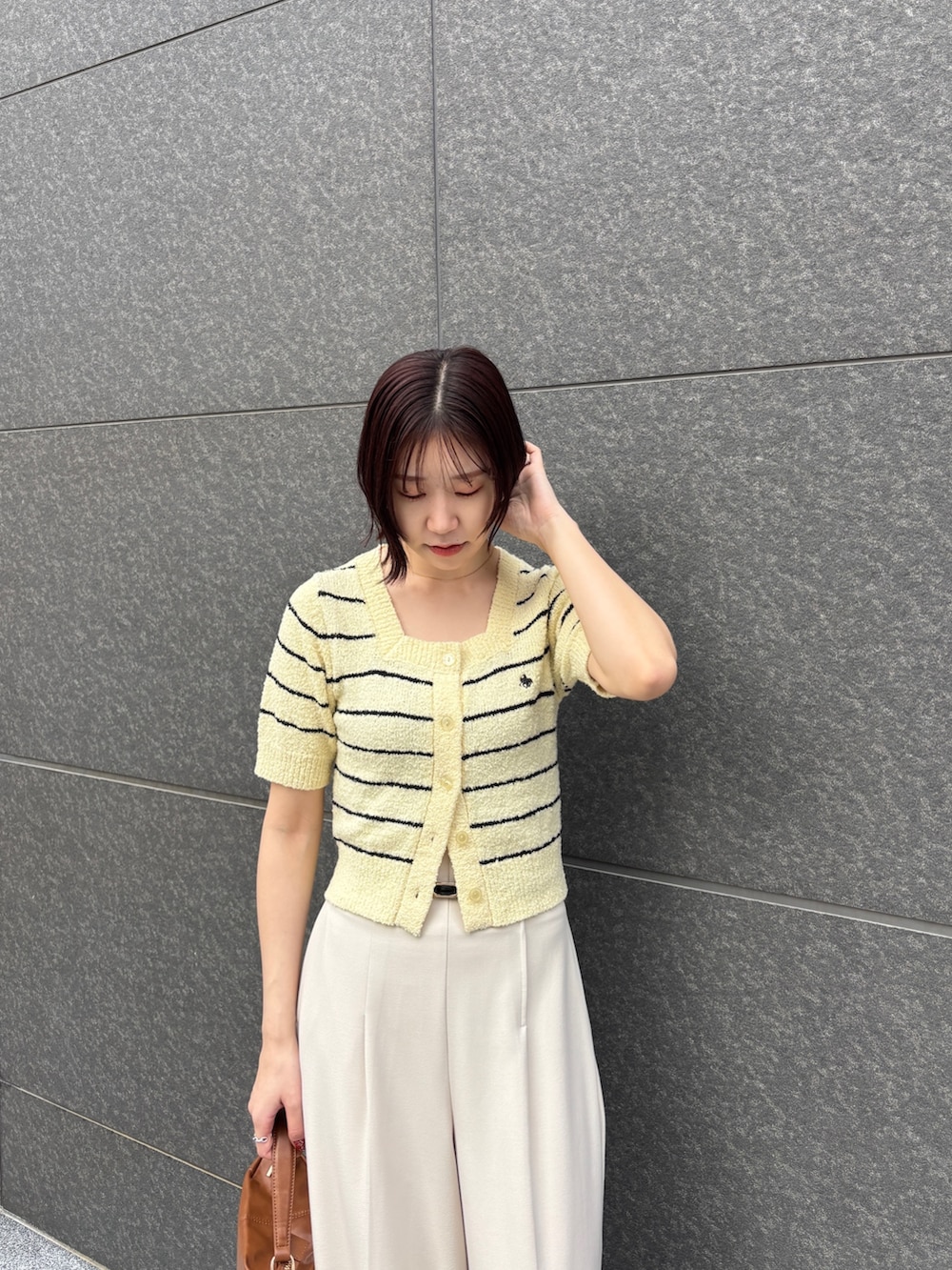 イエロー系のニット/セーター、ホワイト系のその他パンツ、イエロー系のハンドバッグを着用したレディースの春コーディネートの4枚目の写真