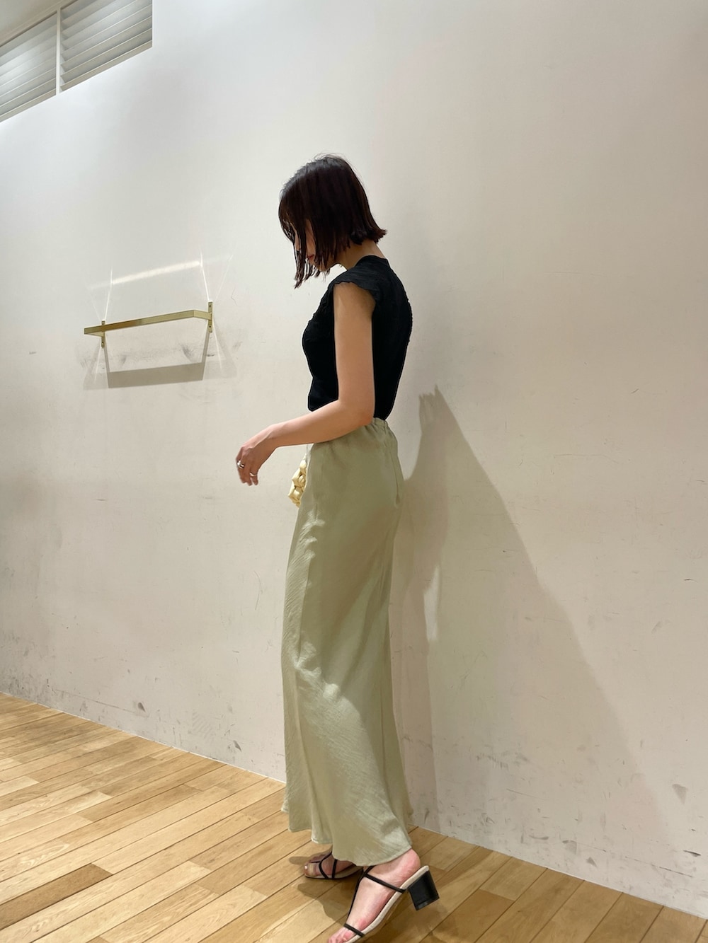 ベージュ系のハンドバッグ、ブラック系のサンダル、グリーン系のスカートを着用したレディースの夏コーディネートの4枚目の写真