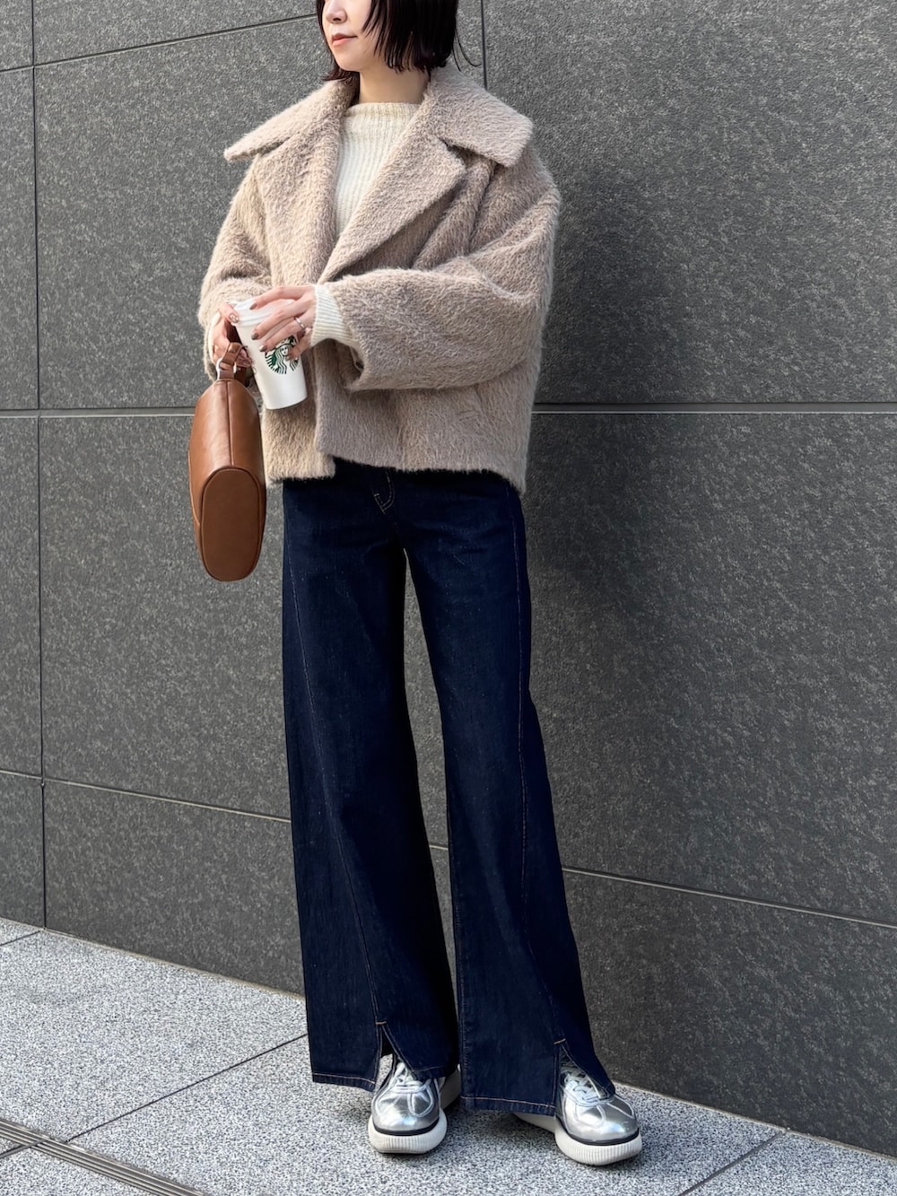 ブルー系のデニムパンツ、ベージュ系のその他アウター、ホワイト系のニット/セーターを着用したレディースの冬コーディネートの2枚目の写真