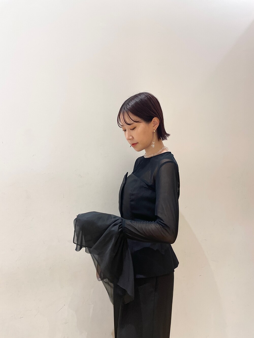 シルバー系のハンドバッグ、シルバー系のパンプス、ブラック系のパンツドレスを着用したレディースの秋コーディネートの8枚目の写真