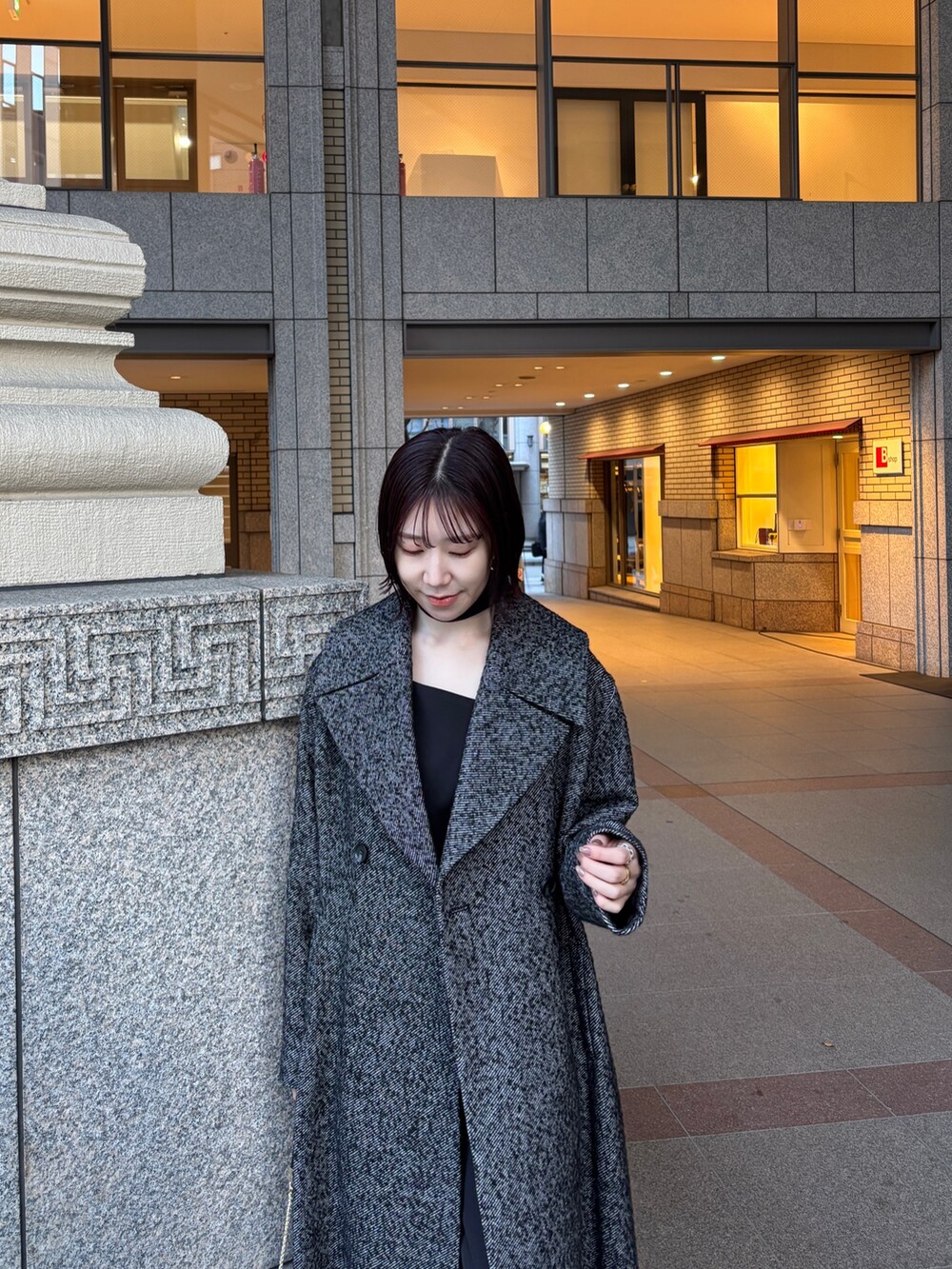 ブラック系のドレス、ブラック系のチェスターコート、ブラック系のハンドバッグを着用したレディースの冬コーディネートの4枚目の写真