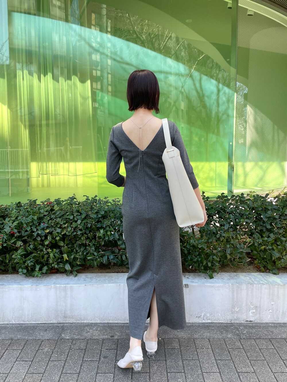 グレー系のワンピース、ホワイト系のショルダーバッグ、ホワイト系のパンプスを着用したレディースの冬コーディネートの4枚目の写真