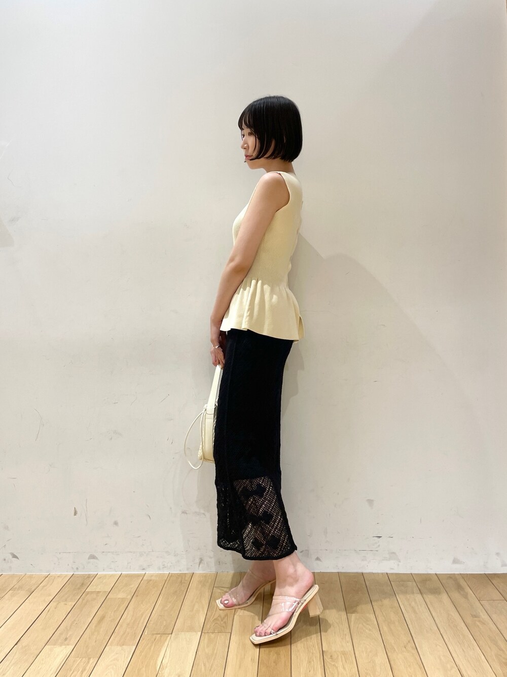 ベージュ系のハンドバッグ、ホワイト系のニット/セーター、ブラック系のスカートを着用したレディースの夏コーディネートの3枚目の写真