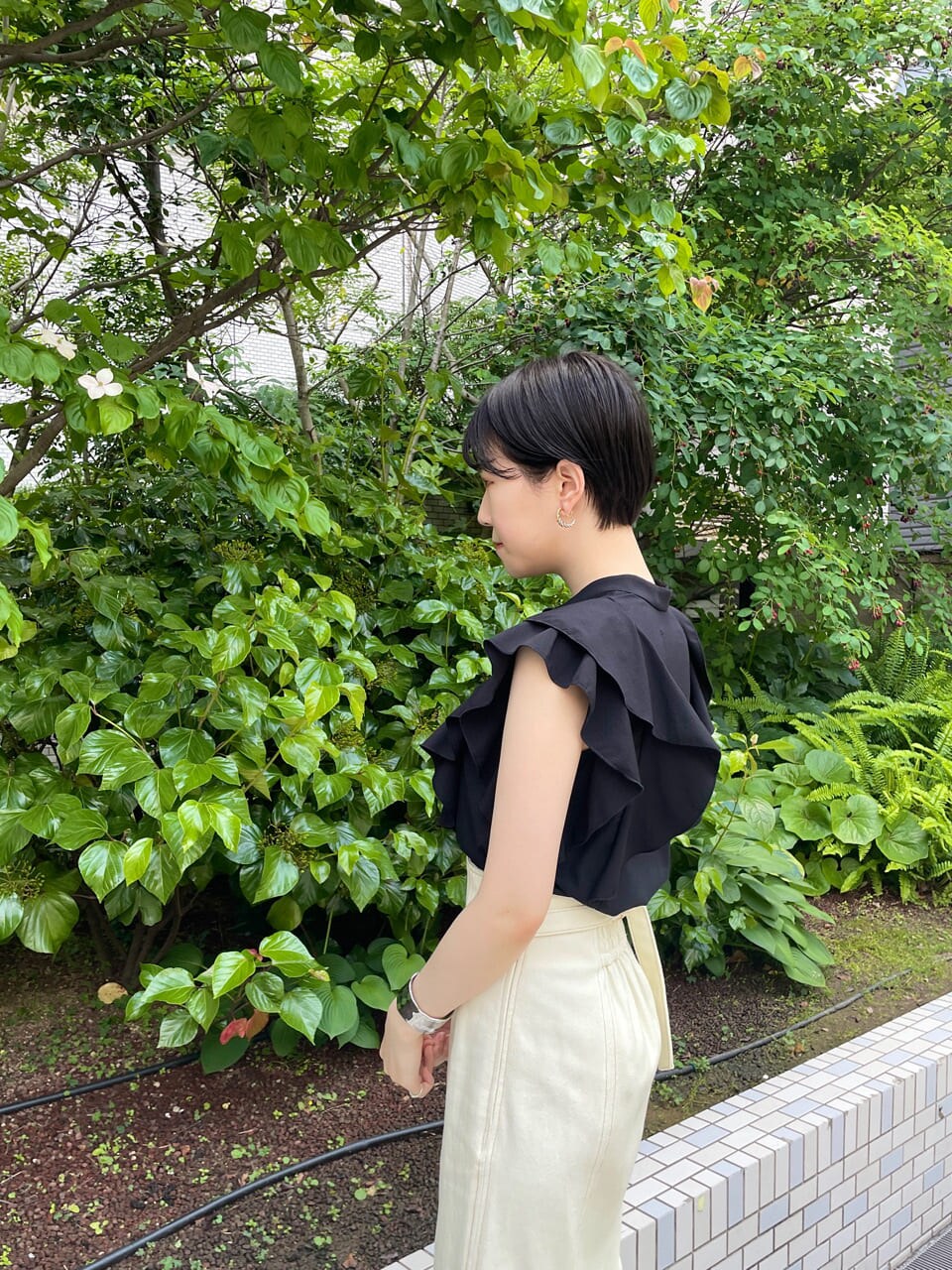 ホワイト系のスカート、ホワイト系のサンダル、ブラック系のシャツ/ブラウスを着用したレディースの夏コーディネートの6枚目の写真