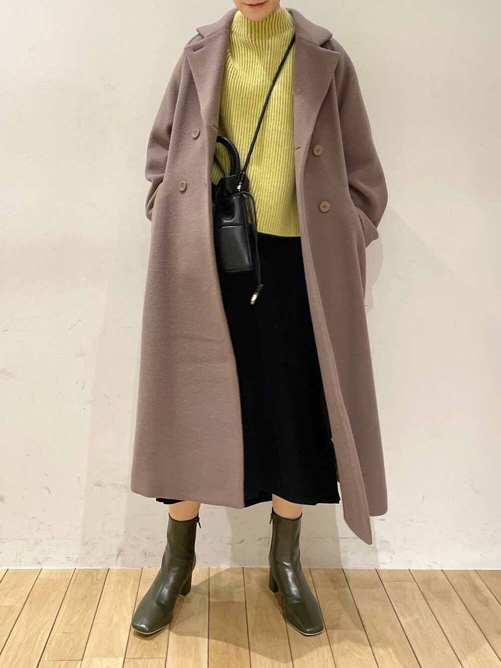 イエロー系のニット/セーター、ブラック系のスカート、ブラック系のハンドバッグを着用したレディースの冬コーディネートの6枚目の写真