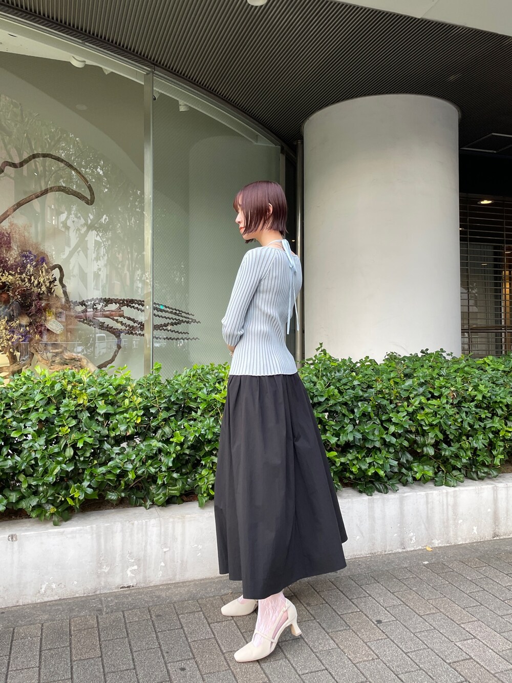 ブラック系のスカート、ブルー系のニット/セーター、ホワイト系のパンプスを着用したレディースの春コーディネートの3枚目の写真