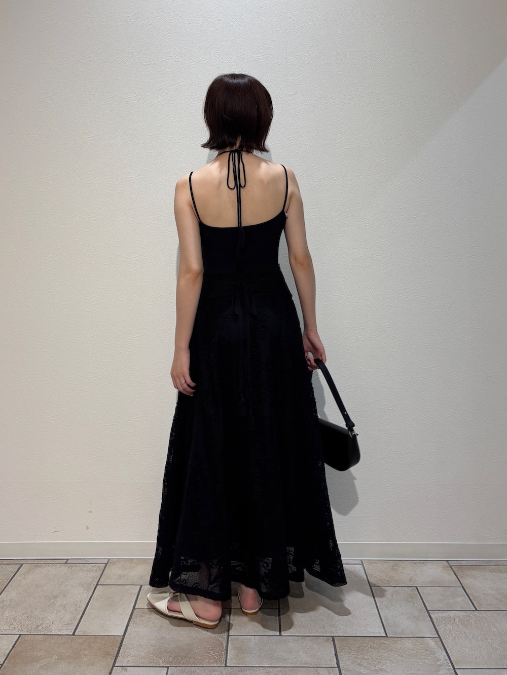 ブラック系のワンピース、ブラック系のハンドバッグ、ホワイト系のサンダルを着用したレディースの夏コーディネートの3枚目の写真
