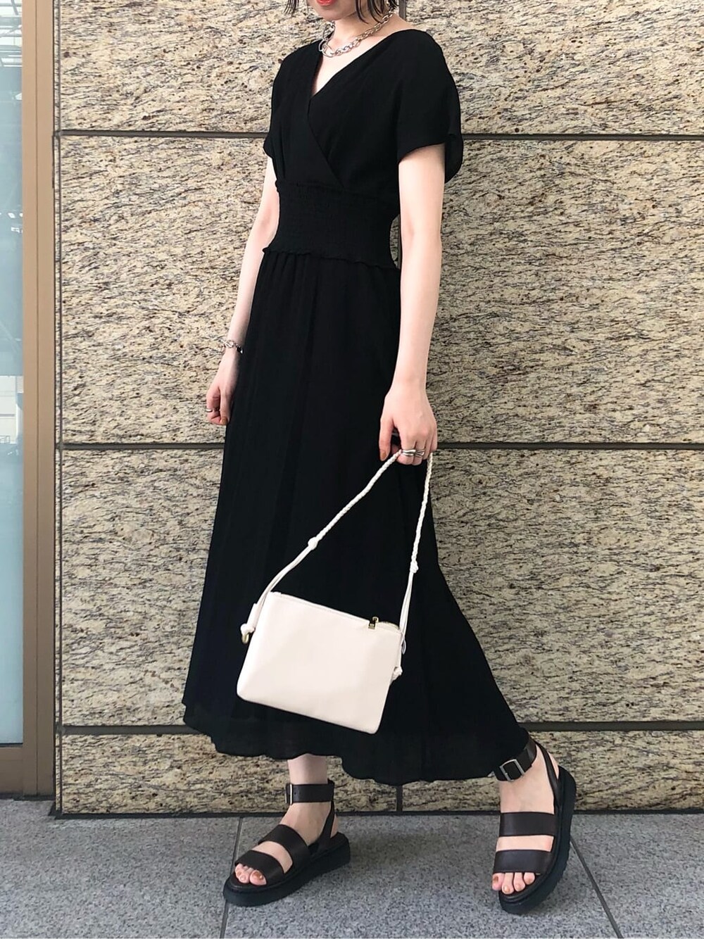 ブラック系のワンピース、ブラウン系のサンダル、シルバー系のブレスレットを着用したレディースの夏コーディネートの2枚目の写真