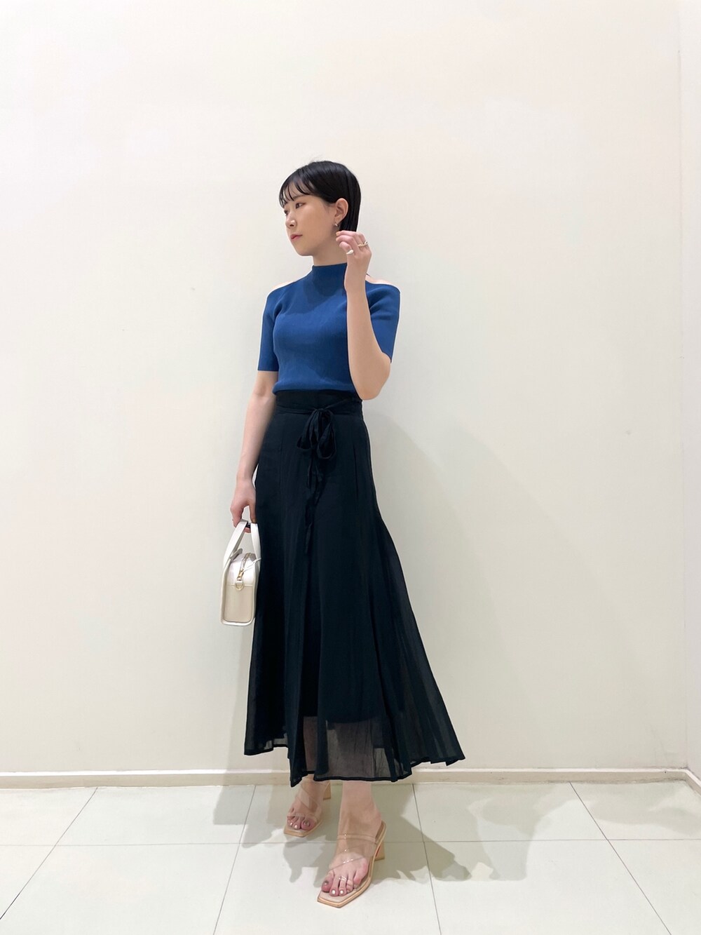 ブラック系のスカート、ホワイト系のショルダーバッグ、その他のサンダルを着用したレディースの夏コーディネートの3枚目の写真