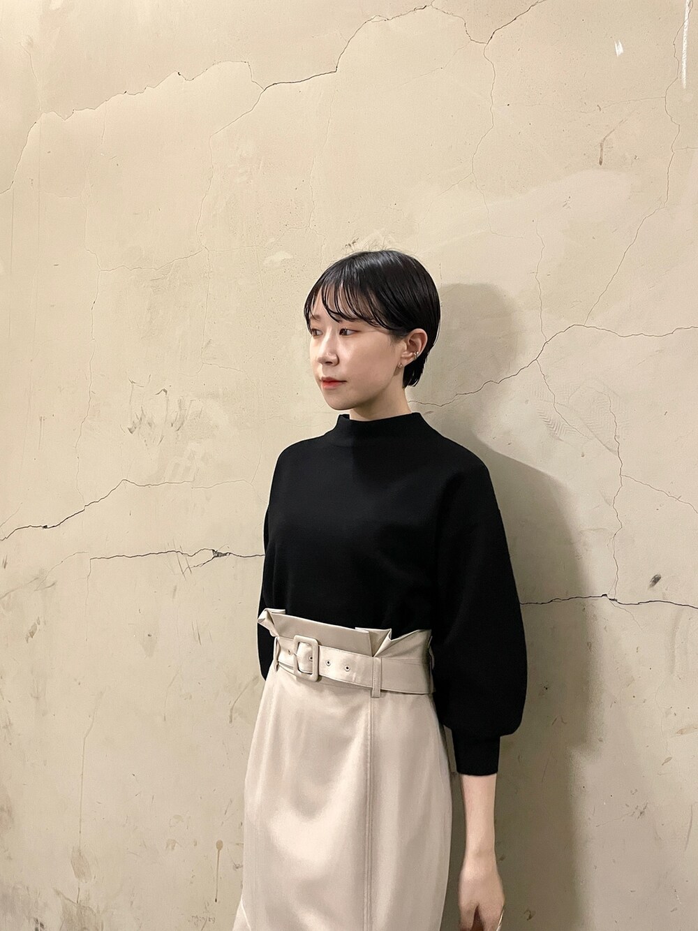 ベージュ系のスカート、ブラック系のニット/セーター、ブラック系のブーツを着用したレディースの秋コーディネートの6枚目の写真