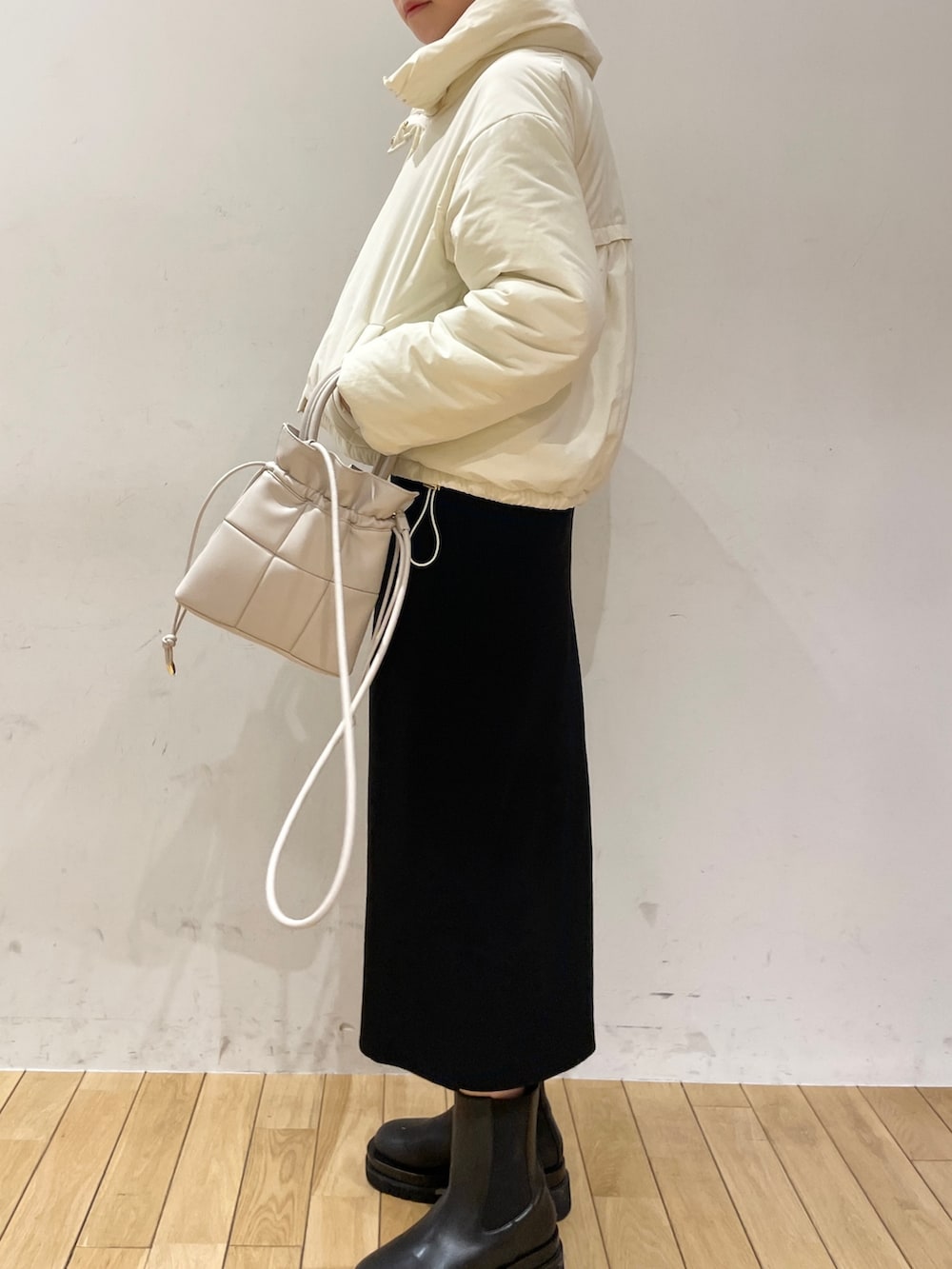 ブラック系のワンピース、ホワイト系のハンドバッグ、ブラック系のブーツを着用したレディースの冬コーディネートの6枚目の写真